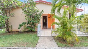 Una casa con ingresso in piastrelle, un piccolo portico e una palma.