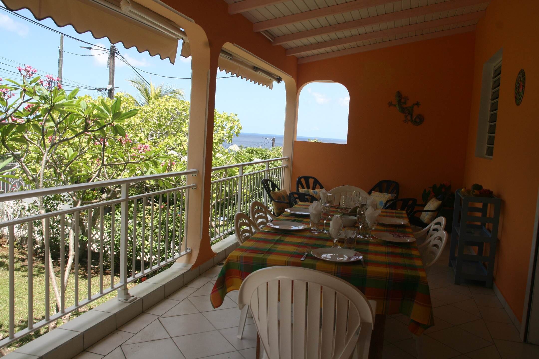 A dining area with a table set for four, white chairs, and a view of the ocean through a window.