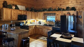 Cucina di una baita in legno con isola centrale, pensili in legno, frigorifero, fornello e lavello.