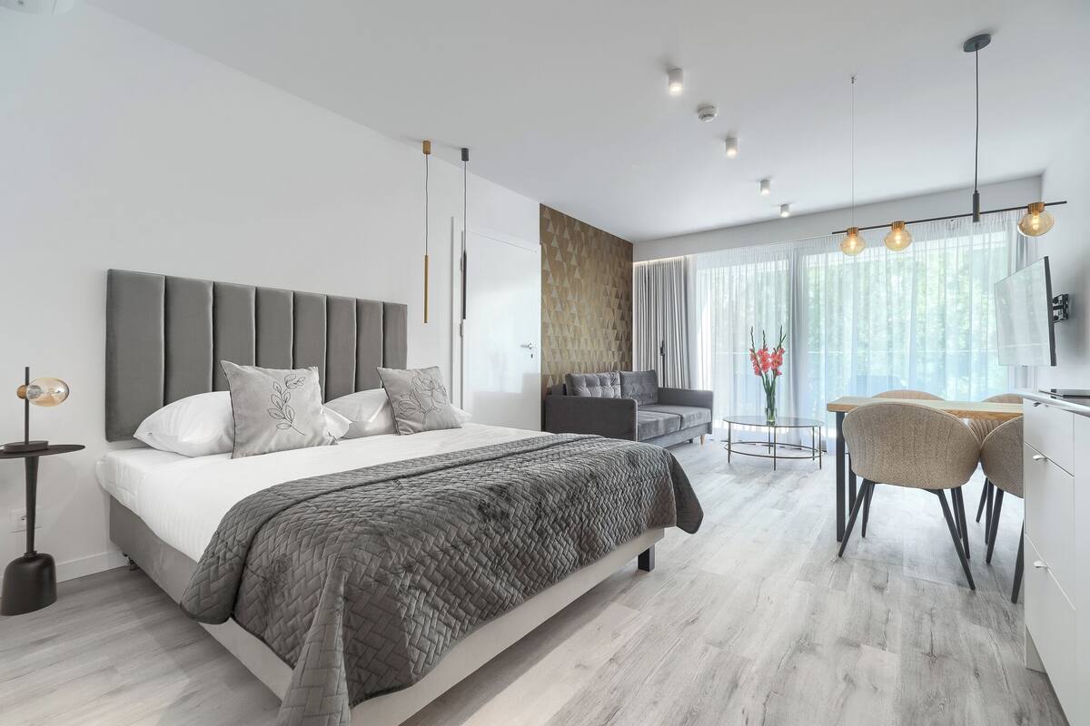 A modern bedroom with a large bed, bedside tables, a desk, and a chair.