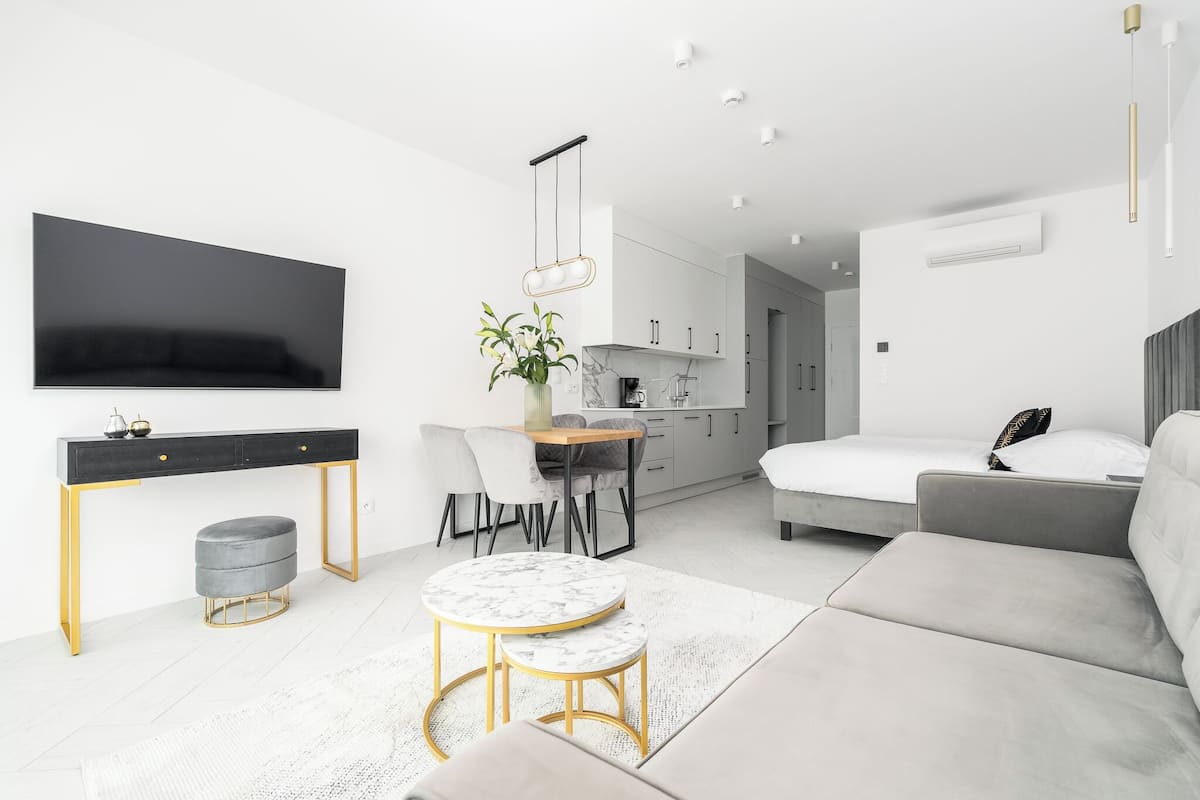 A modern, minimalist living room with a sofa, a round table, and a TV mounted on the wall.