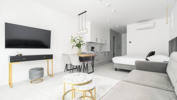 Een moderne, minimalistische woonkamer met een bank, een ronde tafel en een aan de muur bevestigde televisie.
