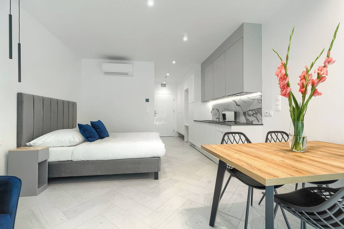 A modern bedroom with a bed, bedside table, and a small desk area.