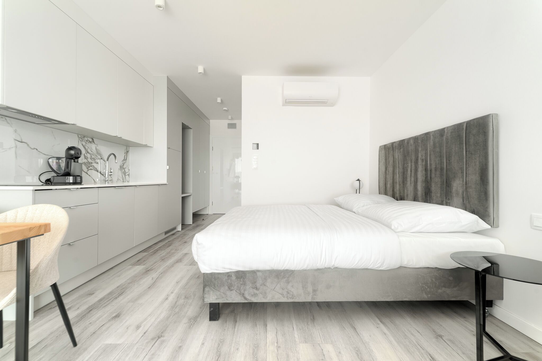 Een moderne slaapkamer met een bed, nachtkastje en een bureau met stoel.