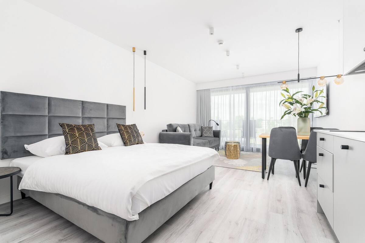 A modern bedroom with a large bed, a desk, and a chair.