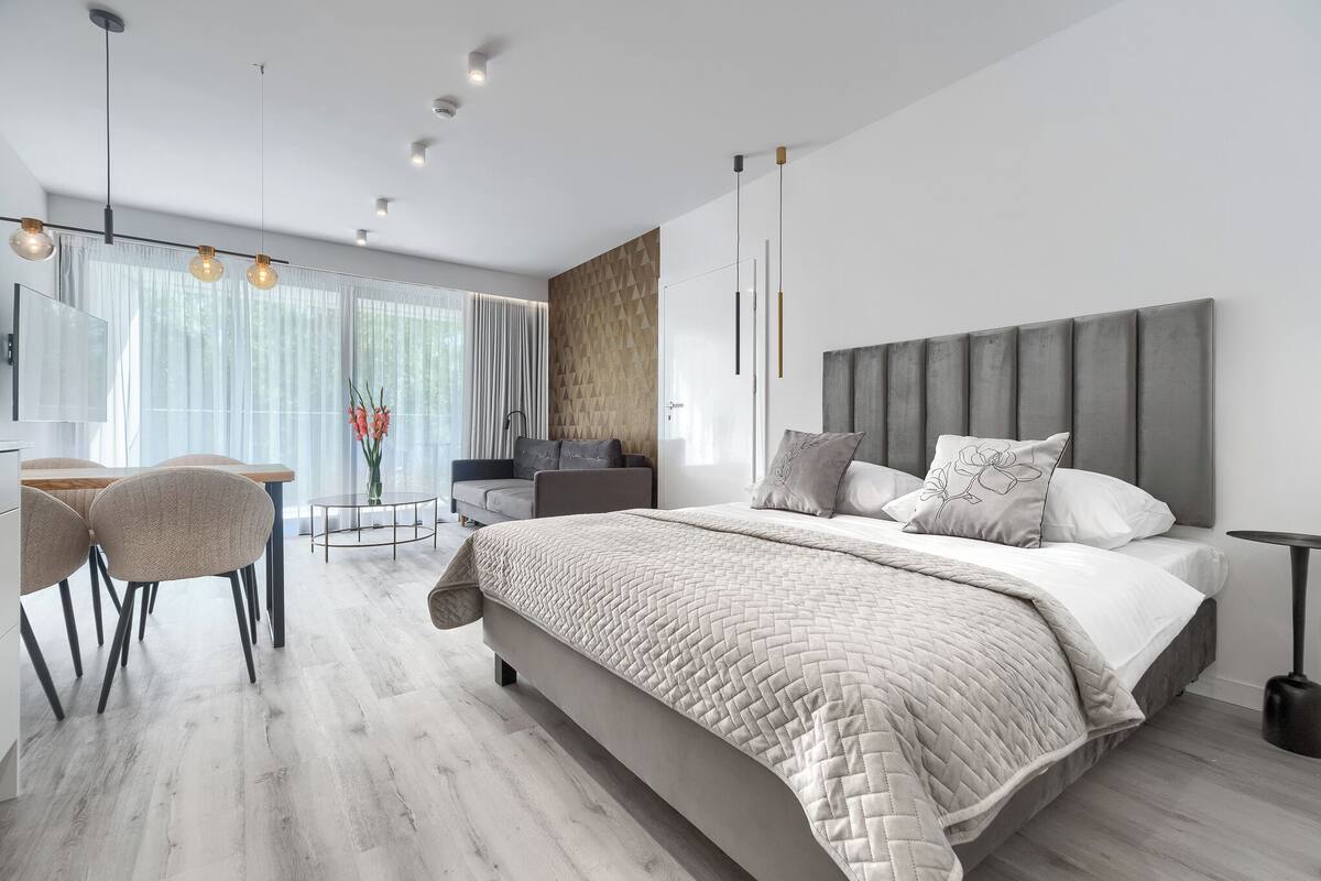 A modern bedroom with a large bed, a desk, and a dining area.