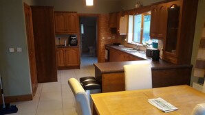A kitchen with wooden cabinets, a dining table, and a kitchen island. - Slieve Anierin House (Gortnawaun)