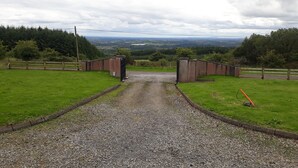 A gravel driveway leading to a gated entrance with a view of a rural landscape. - Slieve Anierin House (Gortnawaun)