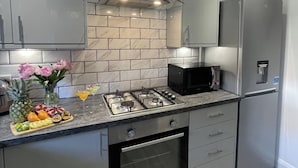 Una cucina moderna con piano cottura a gas, microonde, frigorifero e pannello di schienale in marmo.