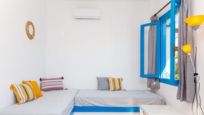 Une chambre avec deux lits, une petite table, une lampe et une fenêtre avec des rideaux.