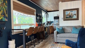 A modern kitchen with a dining area, a sofa, and a painting on the wall. - Lakeside Living with HotTub, Kayaks, Paddleboard; close to Olympic National Park (Port Angeles)