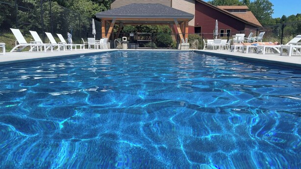 Une piscine aux eaux cristallines, avec des chaises longues et un espace abrité en arrière-plan.