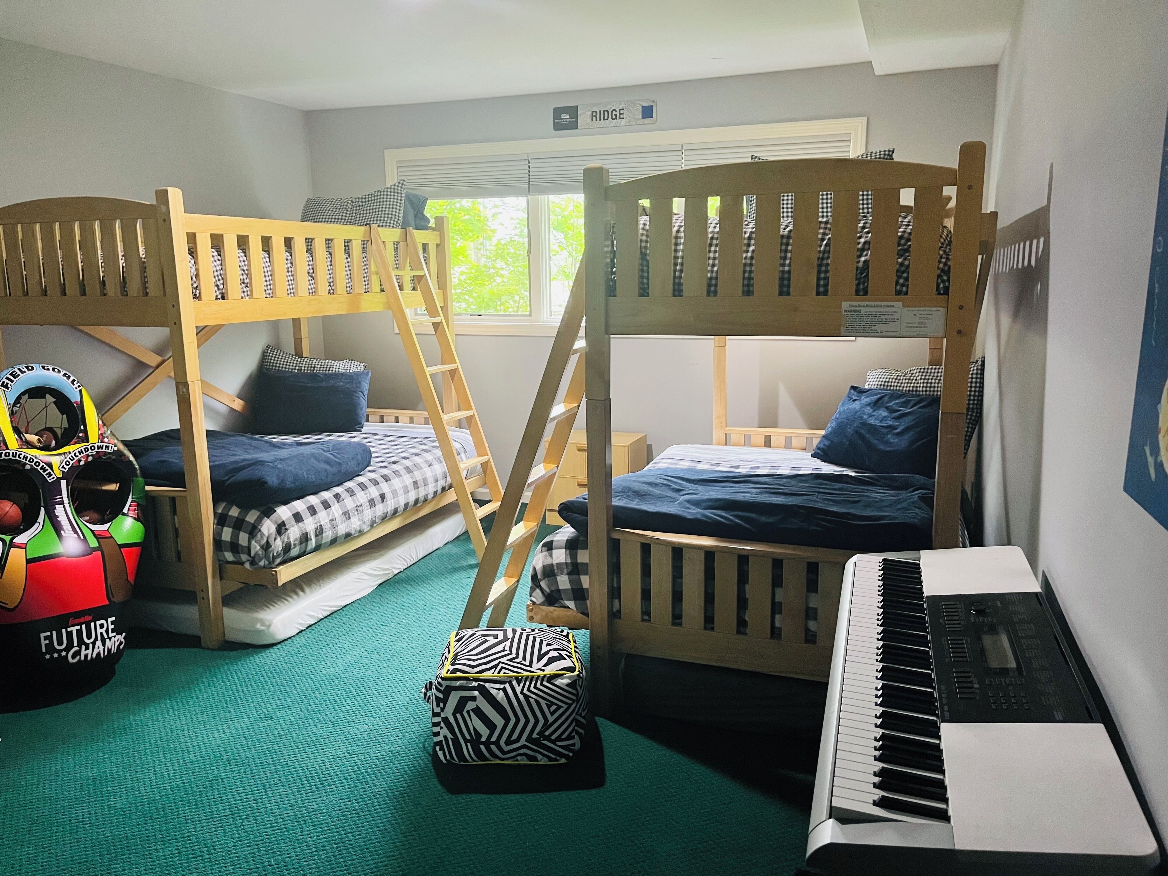 A bunk bed room with a ladder, a small table, a keyboard, and a toy basketball hoop.