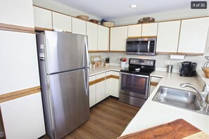 Eine Küche mit einem Edelstahlkühlschrank, einer Mikrowelle, einem Backofen und einem Spülbecken.