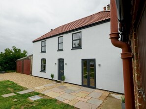 A two-story white building with a red-tiled roof, a front door, and a small garden area with stepping stones and a gravel path. - Perfect for exploring the Wolds and Lincoln - Pass the Keys (Market Rasen)