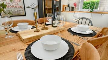 A dining table set with white plates, bowls, and cutlery, accompanied by wine glasses and a decorative centerpiece.
