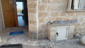 A stone building with a wooden door and a sign reading "Villa La Vida".