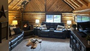 A log cabin interior with a fireplace, leather sofa, and a television. - Little Cabin in the Woods + Disk - Frisbee Golf (Post Falls)
