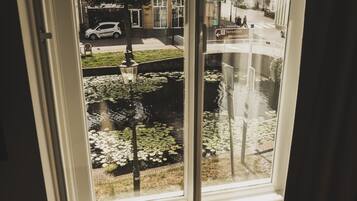 Guests can enjoy a view of the bustling street scene from the comfort of their room, with a water feature and historic buildings visible outside.