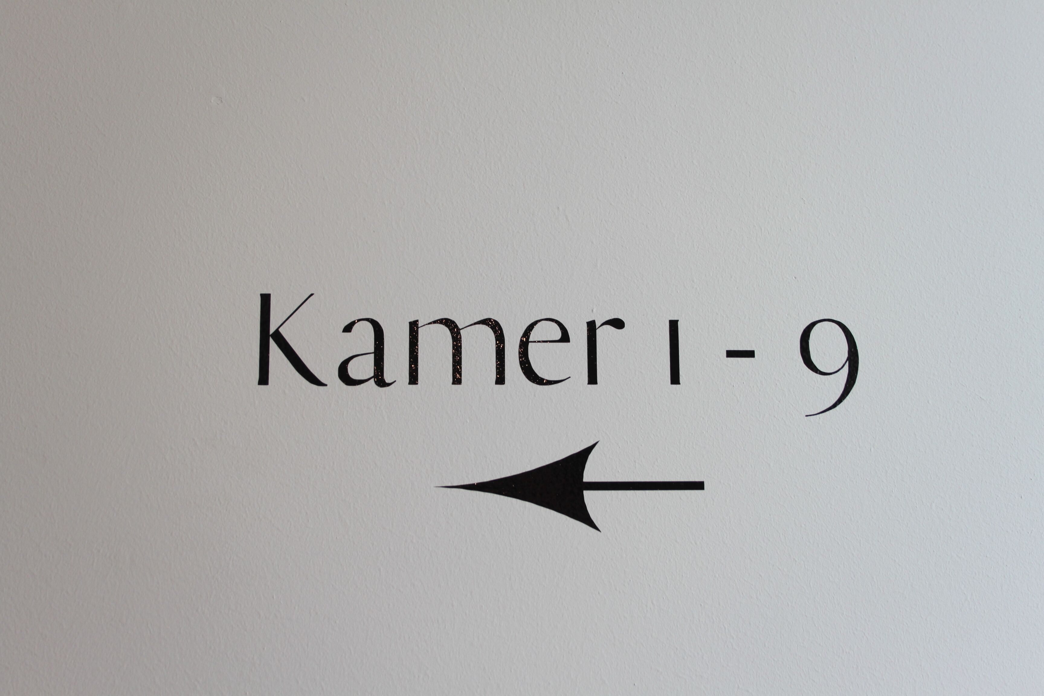 Una señal con el texto 'Kamer 1-9' y una flecha que apunta a la derecha.