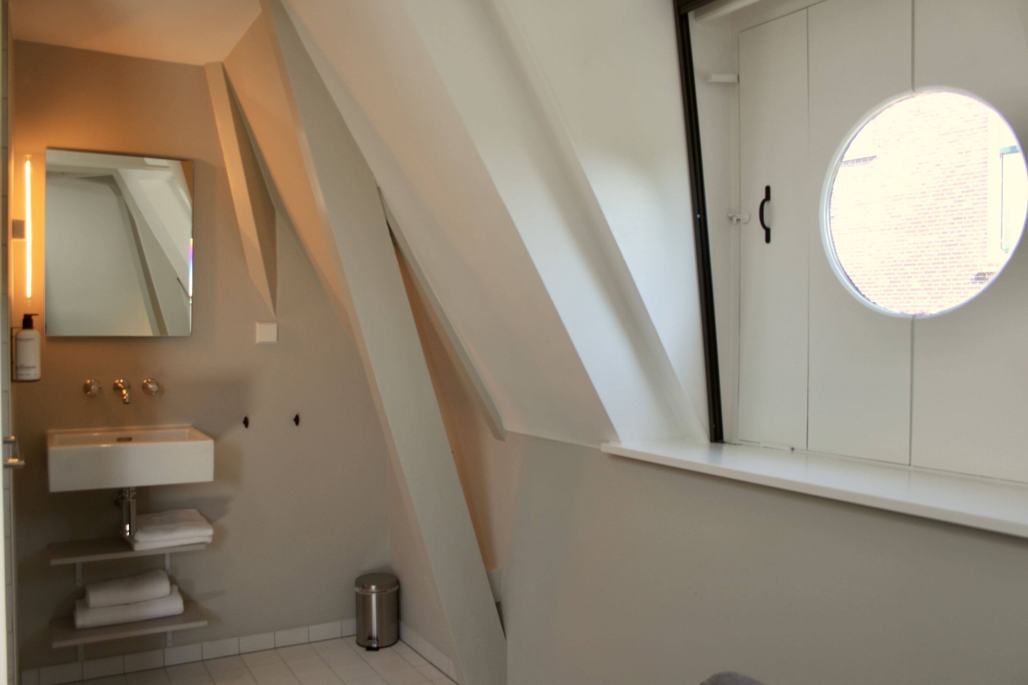 A modern bathroom with a skylight, a large mirror, and a white sink.