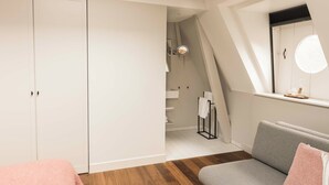 A modern, well-lit room with a grey sofa, a white wardrobe, and a window with a view of a staircase. - Boutique Hotel Weesp (Weesp)
