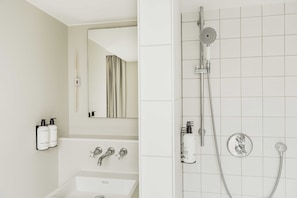 A modern bathroom with a bathtub, a shower with a handheld showerhead, and a mirror.