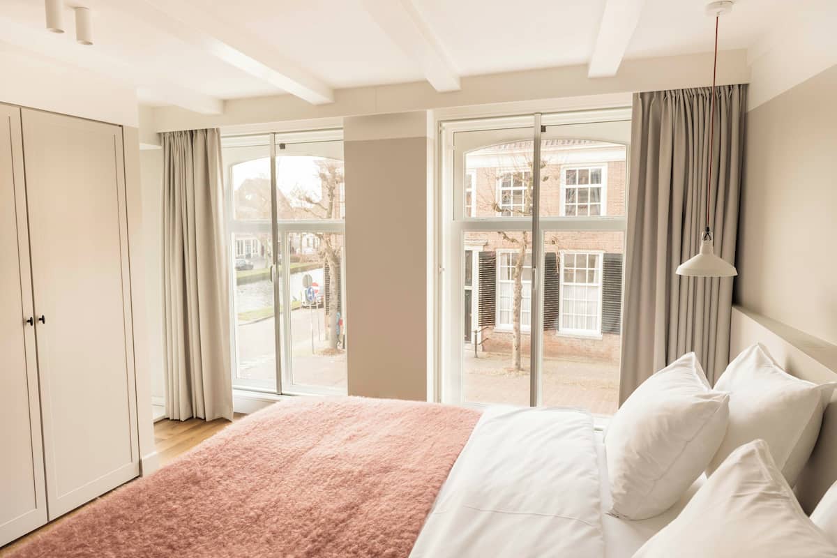 A bedroom with a large bed, a wardrobe, and a view of the outside.