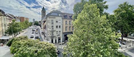 A street view with buildings, trees, and parked cars.