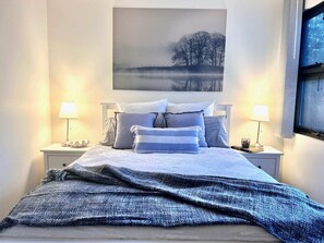 Cozy retreat with a large bed, bedside tables, and a serene artwork above.