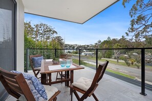 Enjoy the unobstructed view of the surrounding landscape from this balcony with a table and chairs.