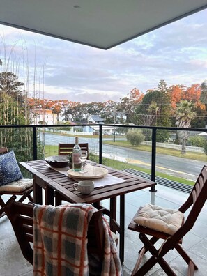 Enjoy a romantic dinner for two on this balcony with a table set amidst a serene residential view.