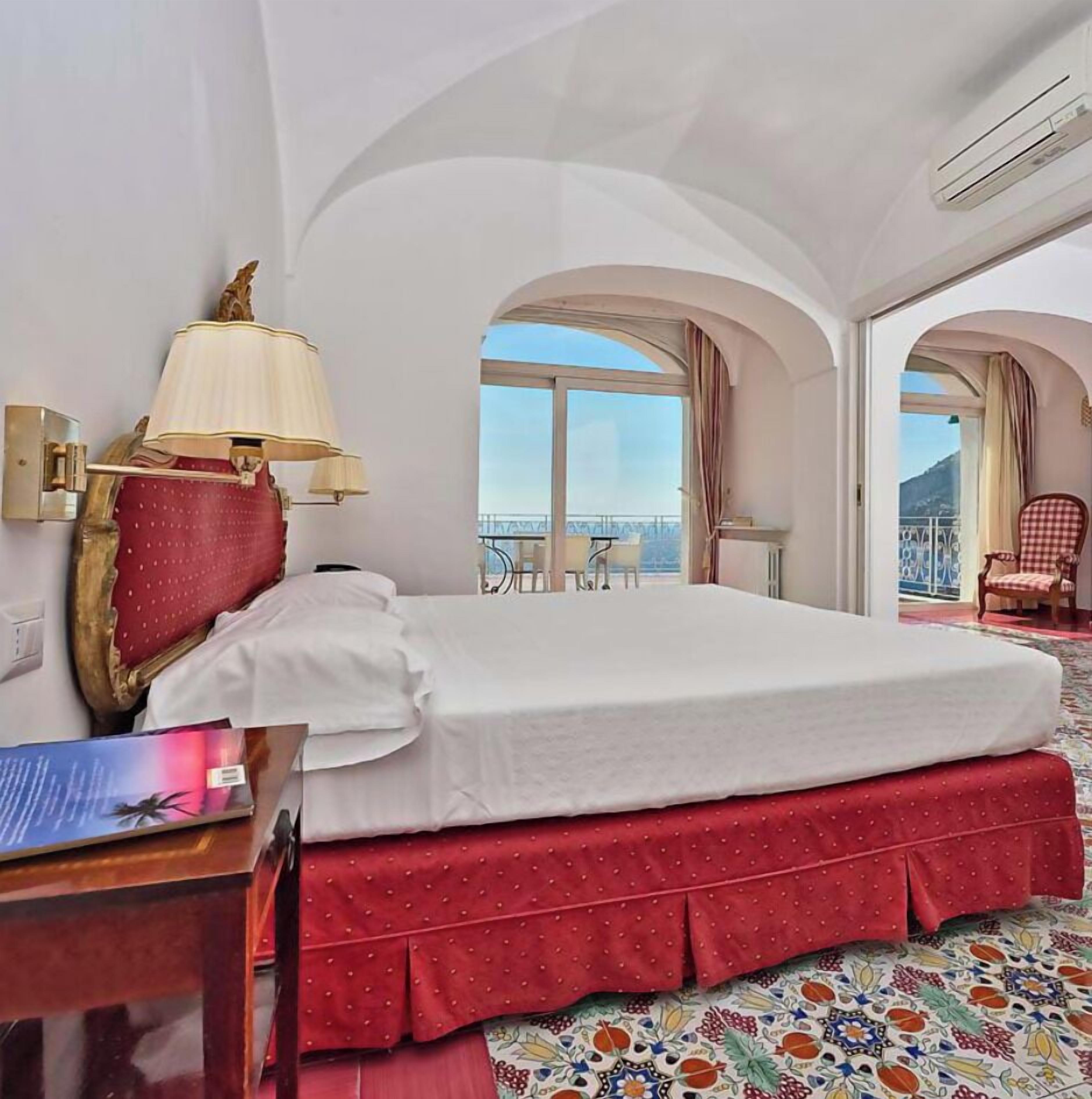 Una camera d'albergo con un letto, una lampada, una sedia e vista sull'esterno.