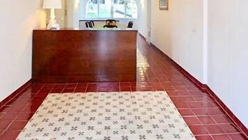 Un'area della reception di un hotel con una scrivania in legno, una moquette fantasia e un soffitto decorato con motivi floreali.