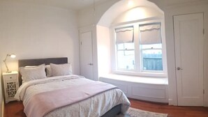 A bedroom with a large bed, a window with a view, and a door. - Lovely Heights Cottage 🌅🌄 (Fenced Yard, Garage) (Houston)