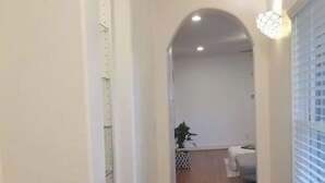 A hallway with wooden flooring, white walls, and a ceiling with recessed lighting. - Lovely Heights Cottage 🌅🌄 (Fenced Yard, Garage) (Houston)