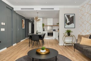 Un saló modern amb zona de menjador, cuina i paret gris amb dibuixos geomètrics.
