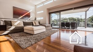 A modern living room with a sofa, ottoman, and a large window. - The Cosmopolitan *1 NIGHT FREE* Stay in the Heart of Sorrento (Sorrento)