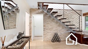 A modern interior with a stone wall, a staircase, and a minimalist decor. - The Cosmopolitan *1 NIGHT FREE* Stay in the Heart of Sorrento (Sorrento)