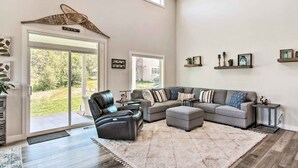 Ein geräumiges Wohnzimmer mit einem Ecksofa, einem Ledersessel und einem großen Fenster.