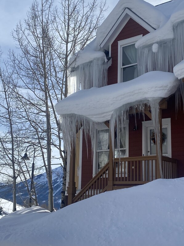 Et hus med istapper fra taget og sne på jorden.
