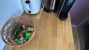 Un plan de travail de cuisine avec un grille-pain, une bouilloire, un radiateur portatif et un panier rempli d’en-cas.