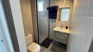 Une petite salle de bain comprenant des toilettes, un lavabo et une douche.