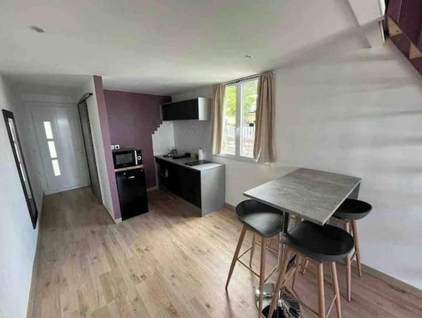 A compact kitchen with a microwave, sink, and small countertop. There is a dining area with a table and two chairs.