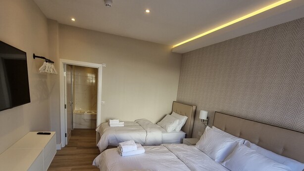 A modern hotel room with a large bed, a bedside table, a TV mounted on the wall, and a bathroom visible through an open door. - Hotel CG London (London)