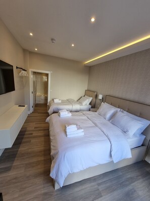 A modern hotel room with a large bed, a bedside table, a TV mounted on the wall, and a bathroom visible through an open door. - Hotel CG London (London)