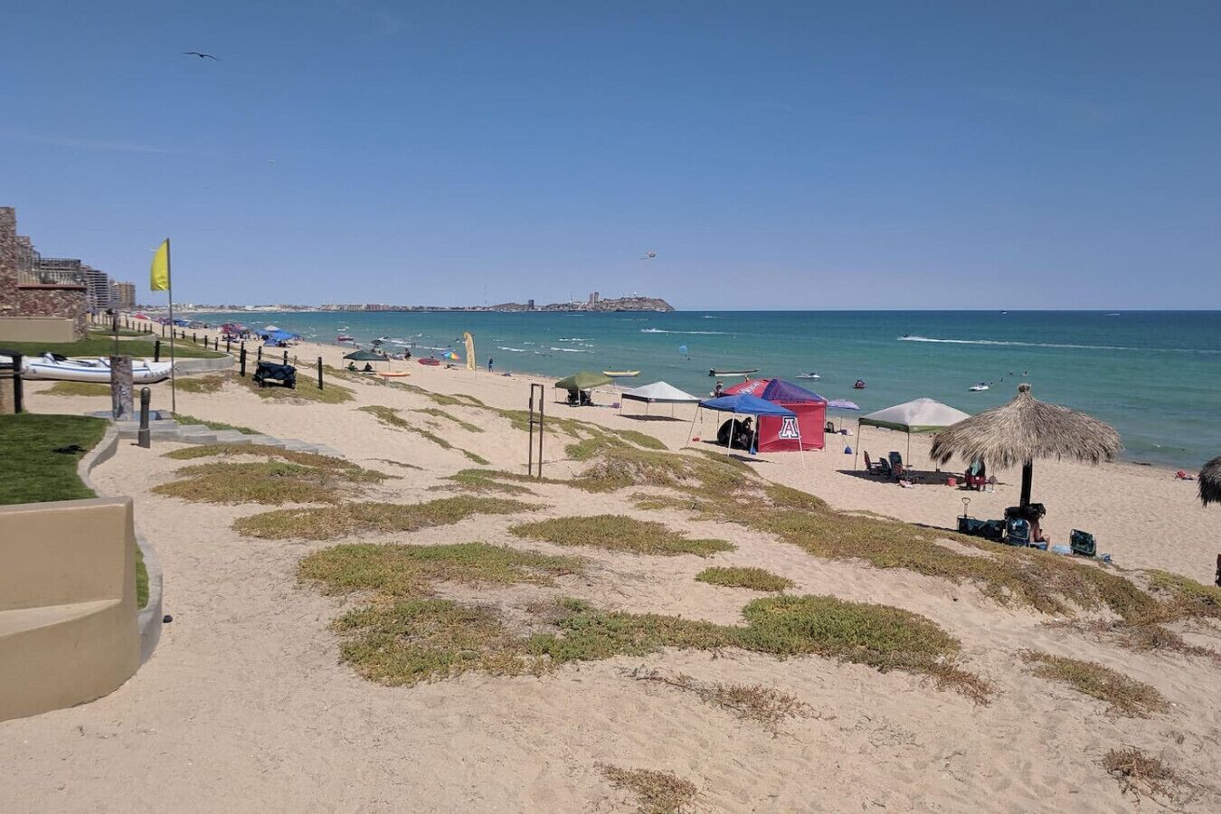Une plage avec des tentes, un drapeau et un ciel dégagé.