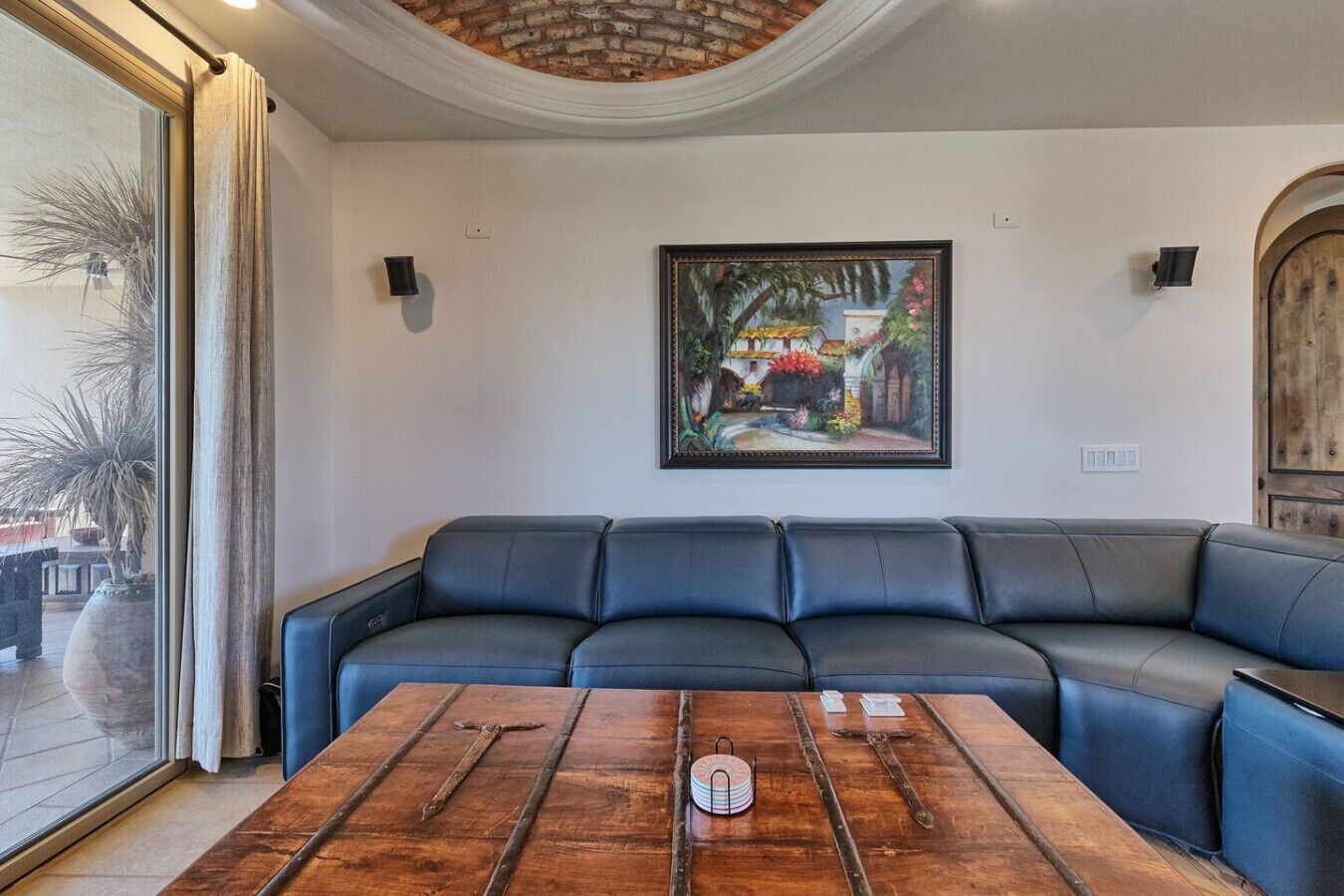 A modern living room with a leather sectional sofa, a wooden coffee table, and a large painting on the wall.