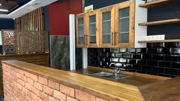 A kitchen with a brick counter, wooden cabinets, and a black backsplash.
