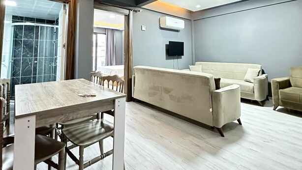 Una sala de estar moderna con una mesa de comedor de madera, sofás beige y un televisor de pantalla plana montado en la pared.
